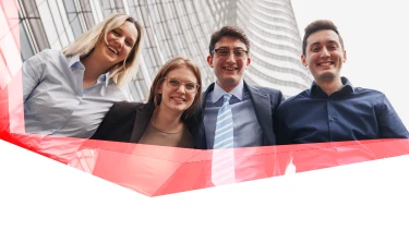 Vier Personen stehen vor einem Gebäude und lächeln in die Kamera, mit rotem transparentem grafischem Element unten im Bild.