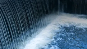 Wasserfall mit fließendem Wasser, das in ein ruhiges Gewässer mündet.