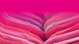 Bunte Textilien in verschiedenen Rottönen und Pinkfarben, die nebeneinander gestapelt sind mit dem Text 