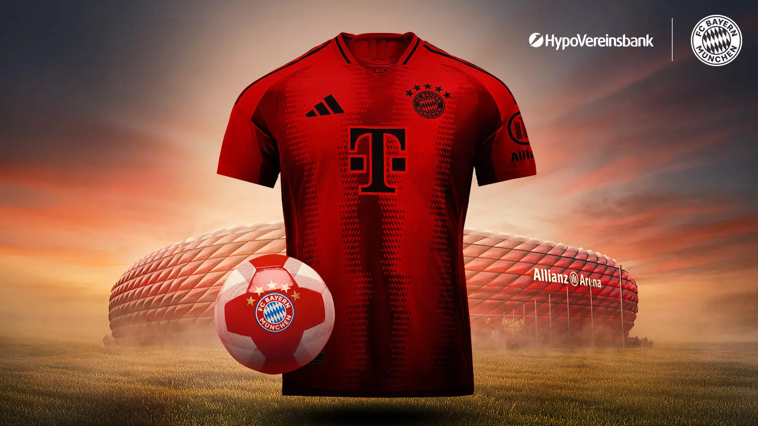 Rotes Trikot des FC Bayern München mit Sponsorenlogos, präsentiert vor der Allianz Arena bei Sonnenuntergang davor ein rot-weißer Fußball mit Vereinslogo.