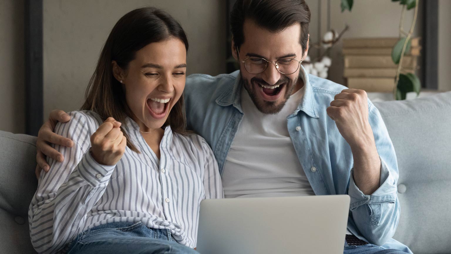 Pärchen jubelnd vor Laptop