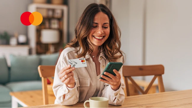 Eine Frau hält eine Kreditkarte in der einen Hand und ein Handy in der anderen.