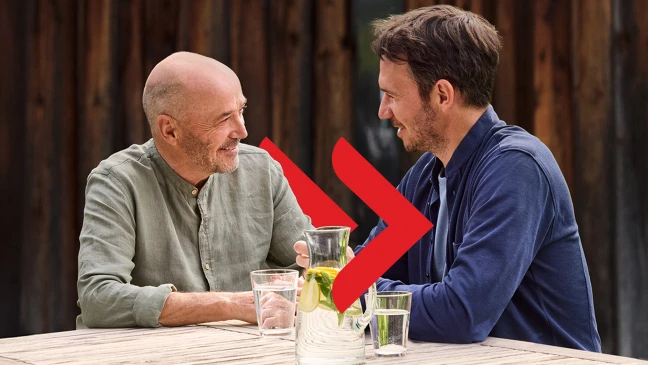 Lächelnde Frau mit Unicreditcard in der Hand sitzt vor einem Laptop