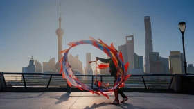 Person wirbelt farbenfrohe Bänder vor der Skyline von Shanghai.