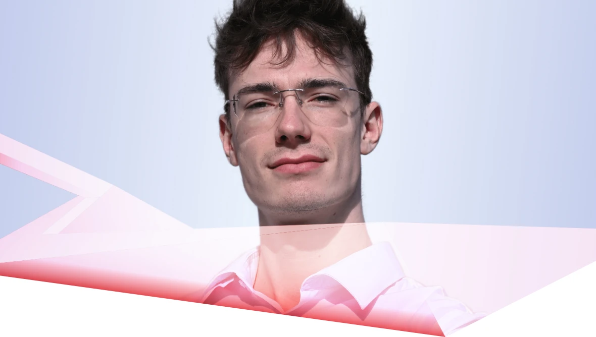 Person with short hair and glasses in front of a light blue background with pink shapes.