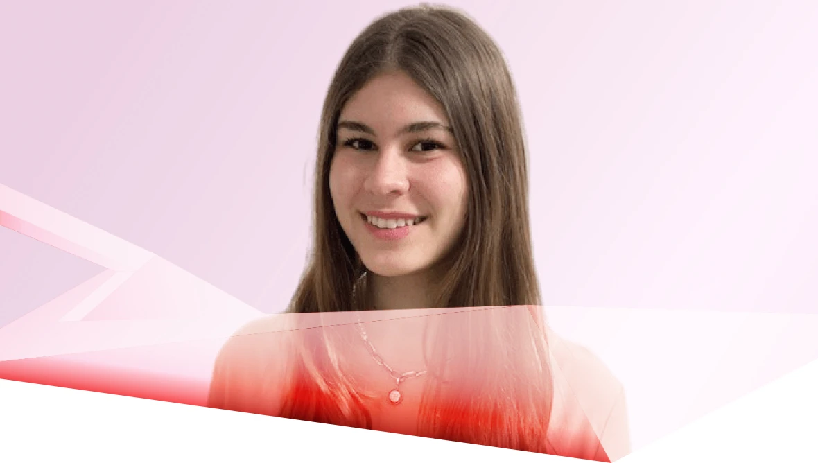Smiling person with long straight hair and necklace, in front of a light pink and white gradient background.