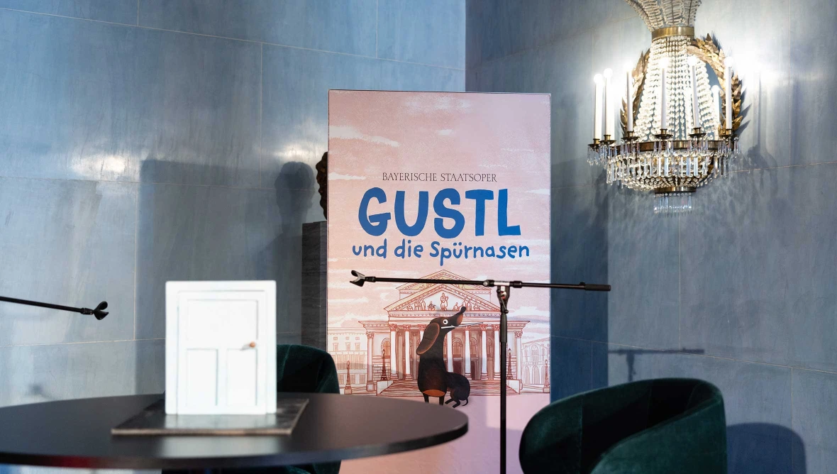 Aufsteller zu Gustl und die Spuernasen steht neben Mikrofonen und einem Modell in einem Innenraum.