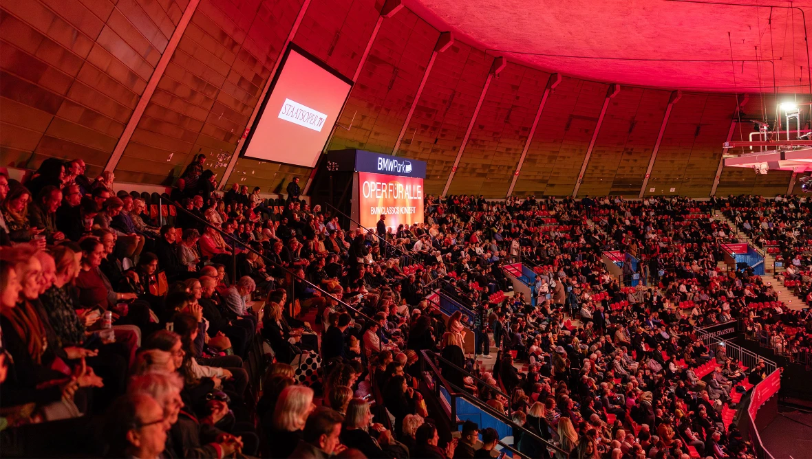 Voll besetzte Ränge einer Tribühne in rotem Scheinwerferlicht
