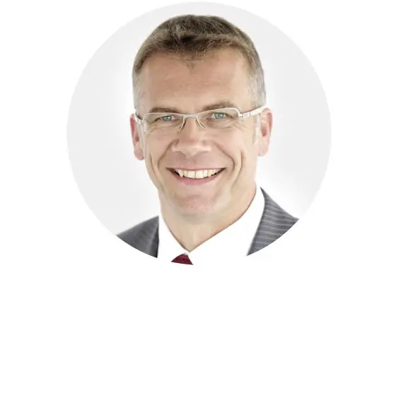 Porträt einer lächelnden Person mit Brille in einem runden Rahmen ohne Text.