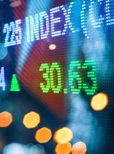 Digitale Anzeige mit grünen Zahlen und Prozentwerten vor verschwommenem Hintergrund mit Lichtreflexionen und Bokeh-Effekten.